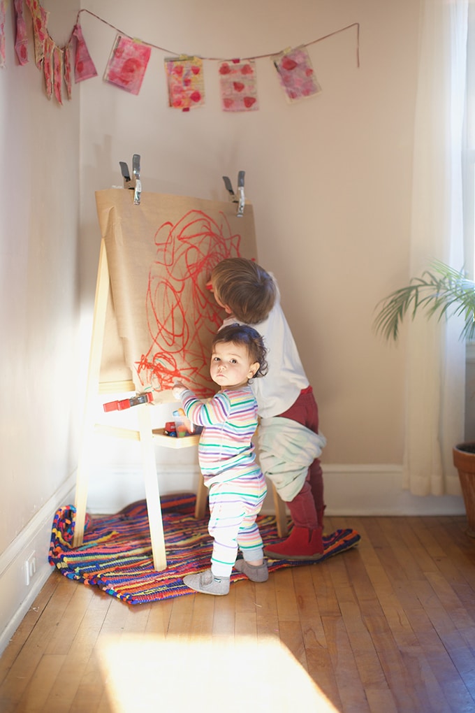 Children painting at easel with paint sticks - Rachel Withers